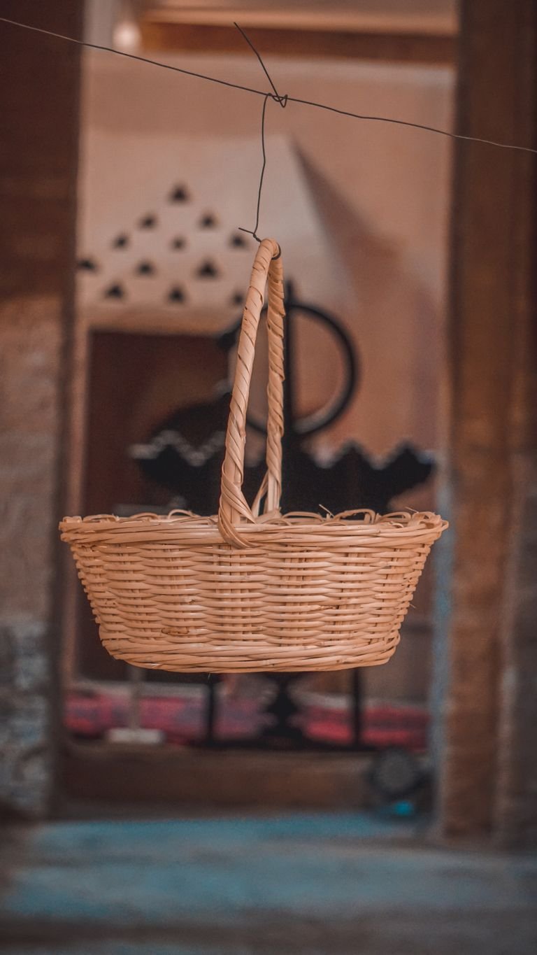 A wicker basket suspended indoors with a blurred rustic background, capturing an earthy and cozy ambiance.