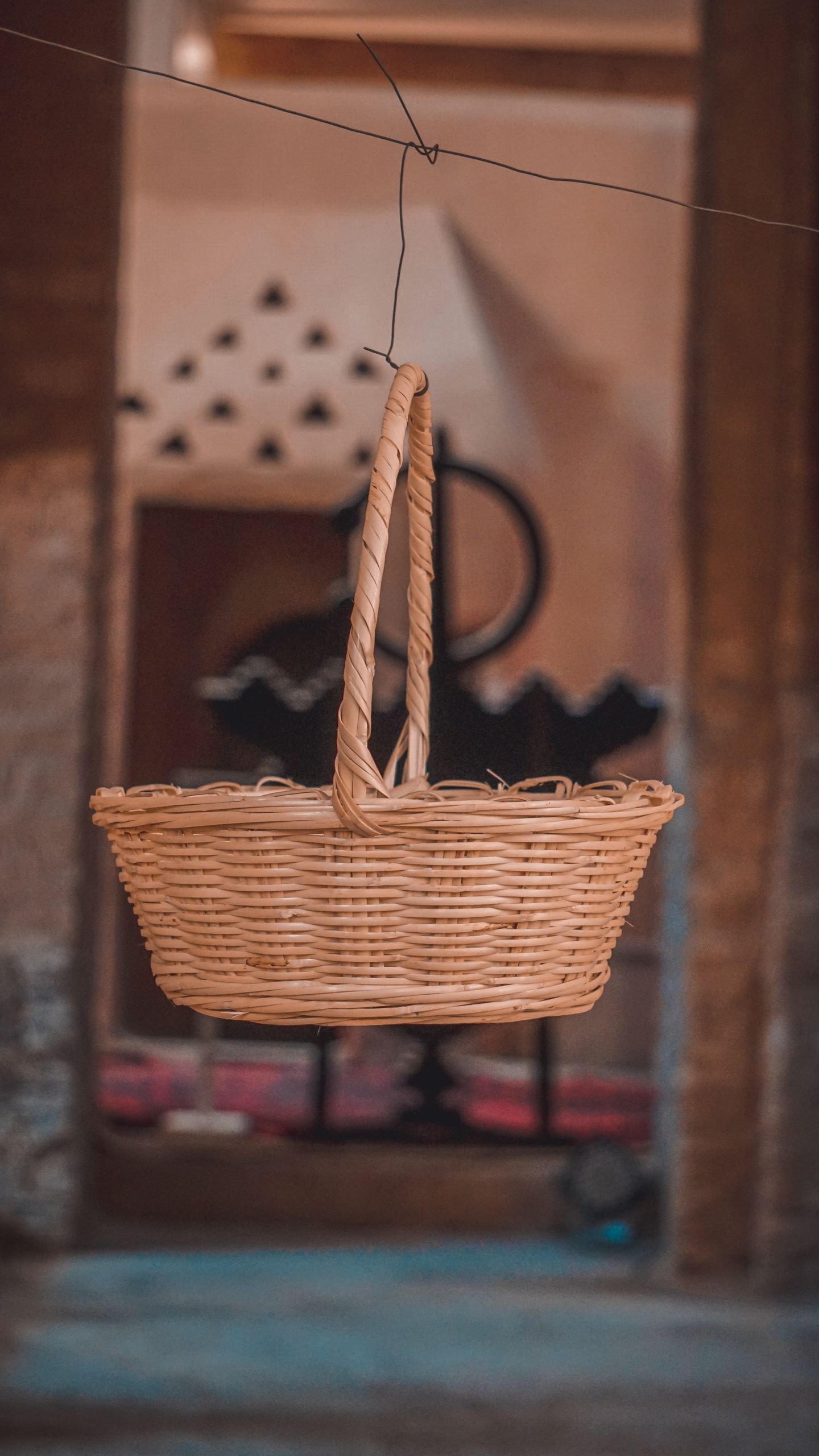 A wicker basket suspended indoors with a blurred rustic background, capturing an earthy and cozy ambiance.