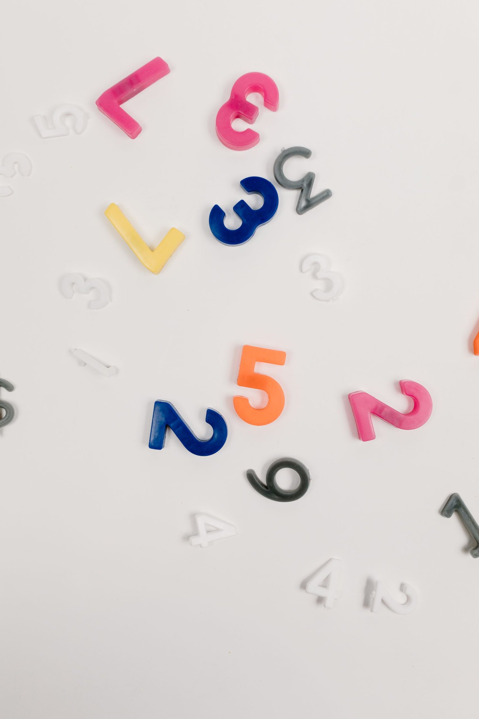Brightly colored plastic numbers scattered on a white surface, ideal for educational and creative concepts.