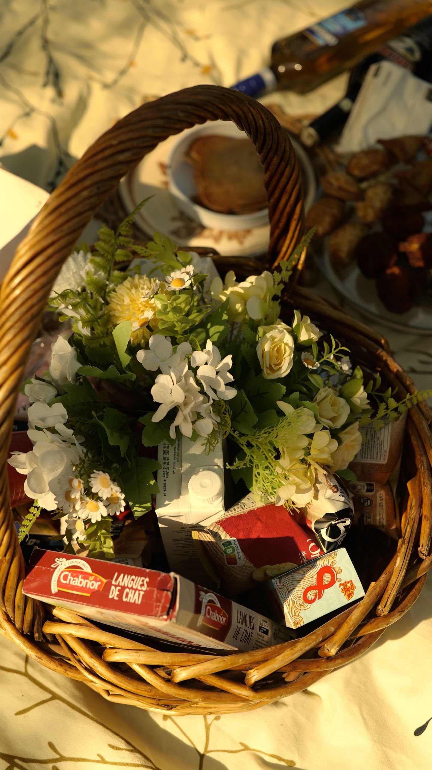 Charming picnic basket filled with flowers and snacks, perfect for a sunny outdoor picnic.