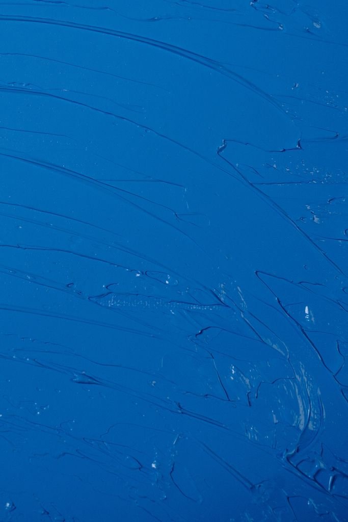 Close-up of a textured abstract painting with deep blue hues and dynamic brush strokes.