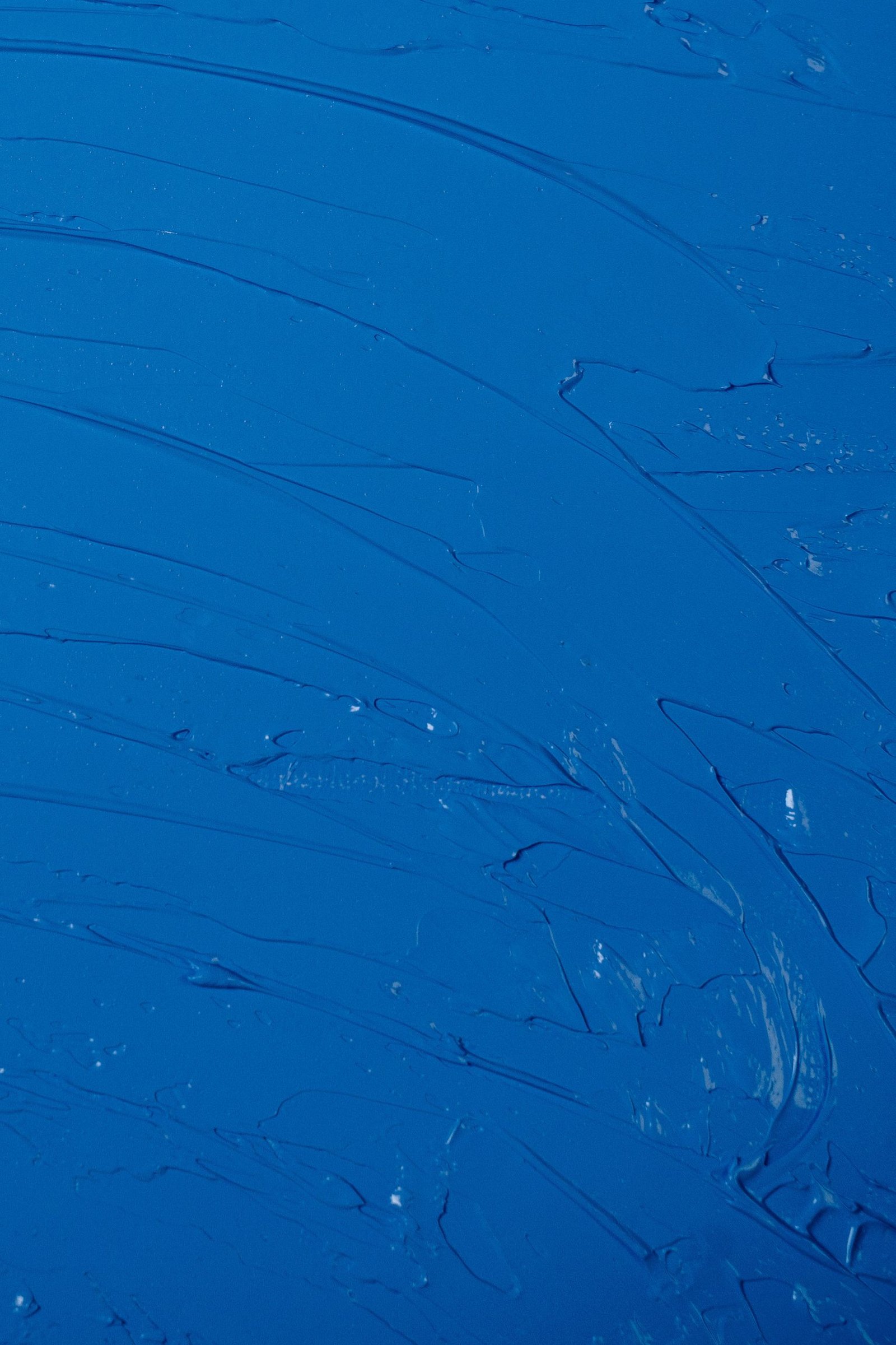 Close-up of a textured abstract painting with deep blue hues and dynamic brush strokes.