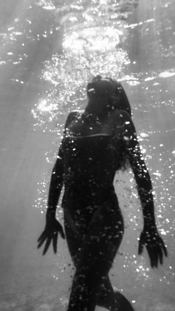 Elegant silhouette of a woman underwater with bubbles in monochrome.