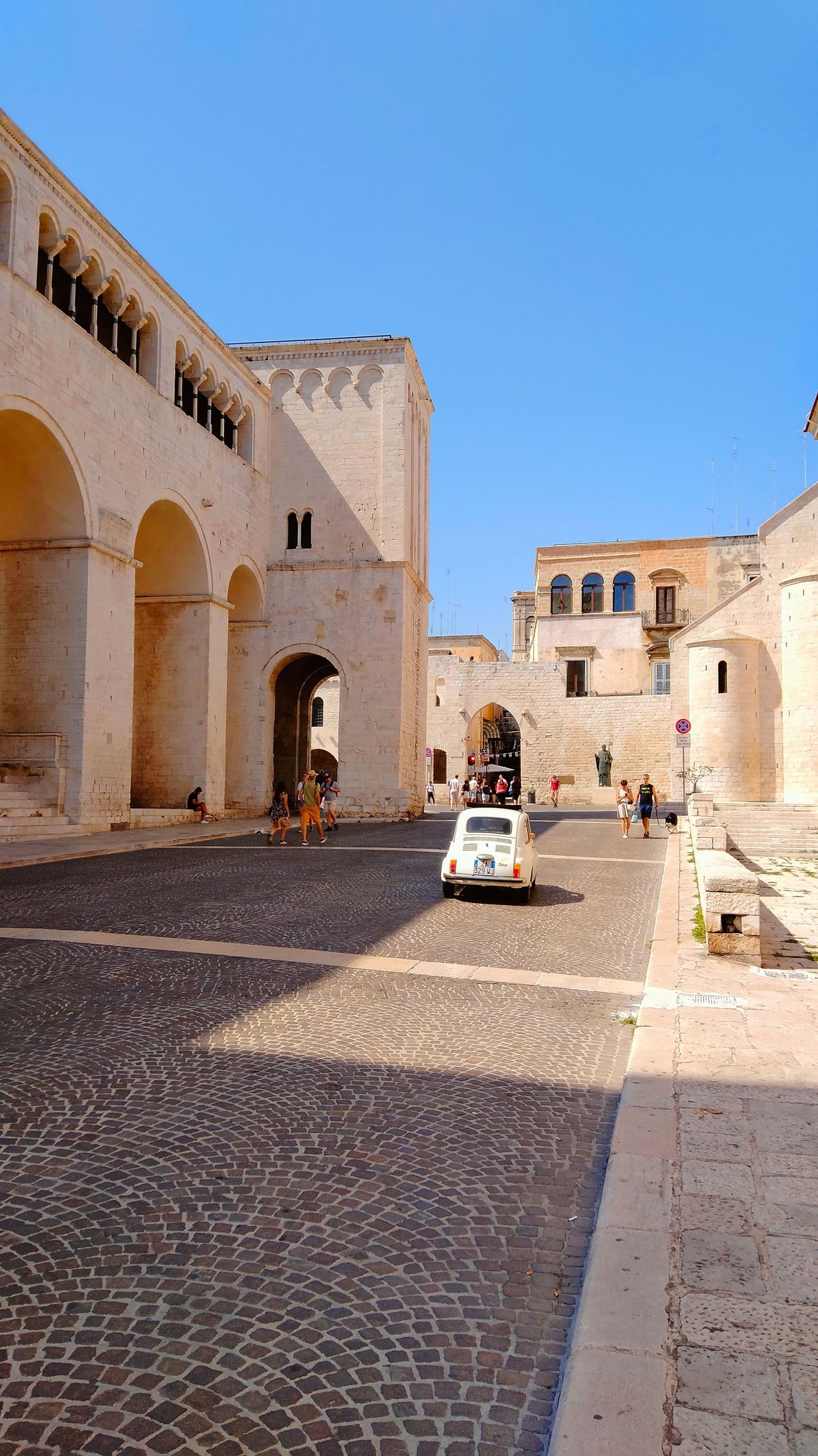 Explore a picturesque cobblestone street in a historic old town with a classic white car.