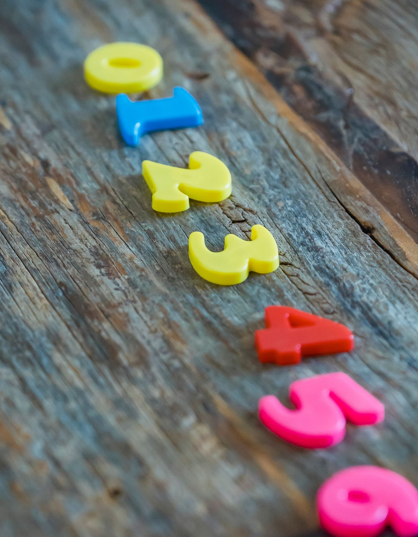 High angle of colorful plastic toy numbers for practicing math for kids on wooden table
