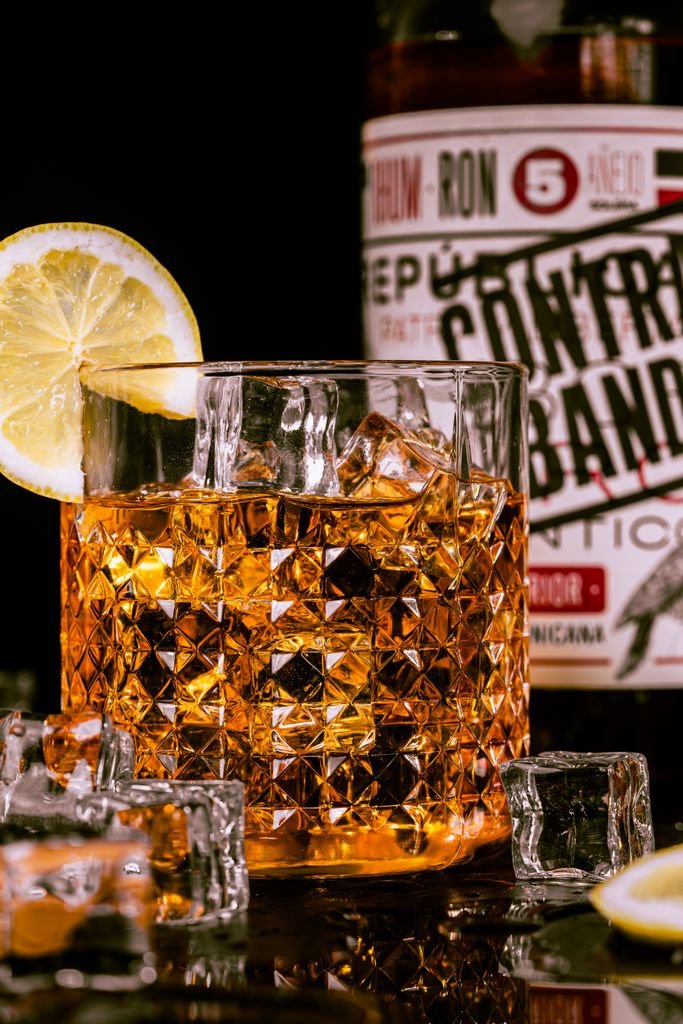 Refreshing amber cocktail served with lemon slice and ice cubes in a crystal glass.