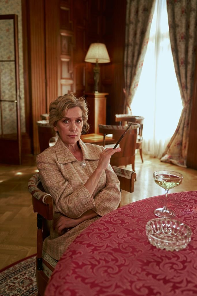 Sophisticated senior woman seated in a luxurious, vintage interior design setting, exuding elegance.