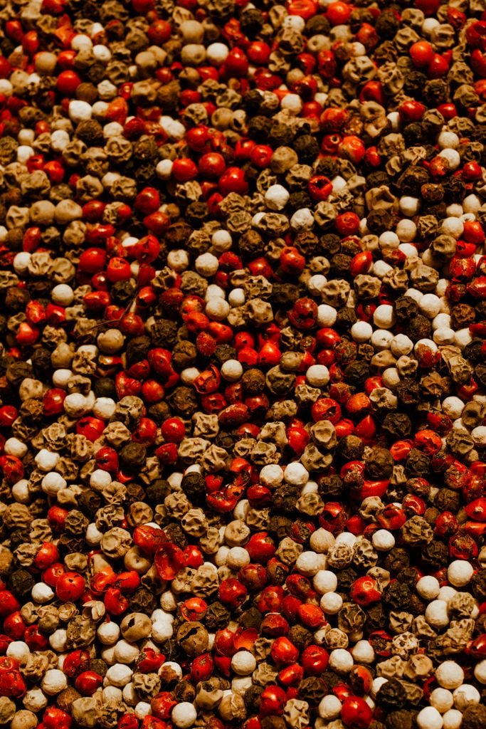 Vibrant close-up of mixed peppercorns showcasing red, white, and black varieties.